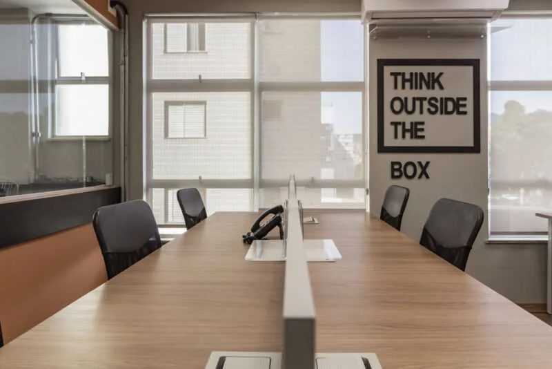 Mesa de reunião com quatro cadeiras e o quadro Think Outside The Box